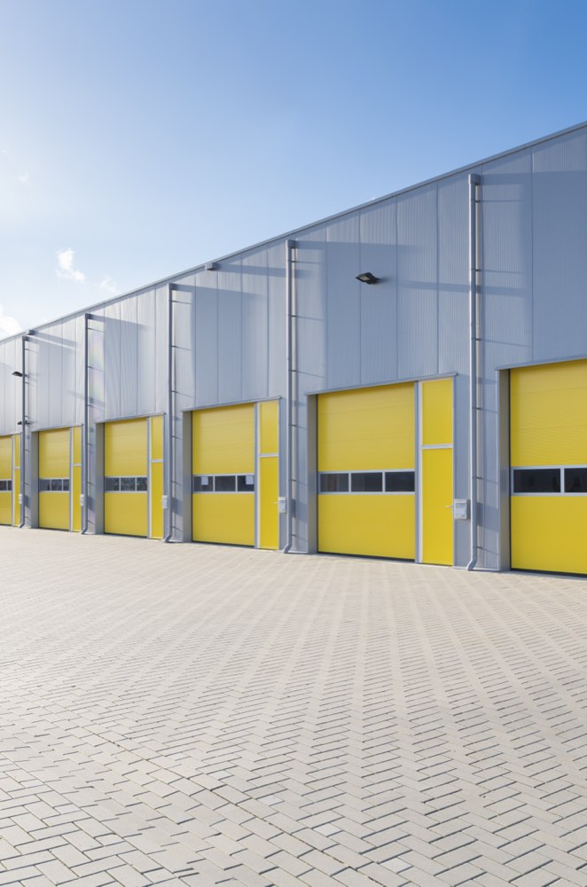 A row of warehouse units with yellow roll-up doors.