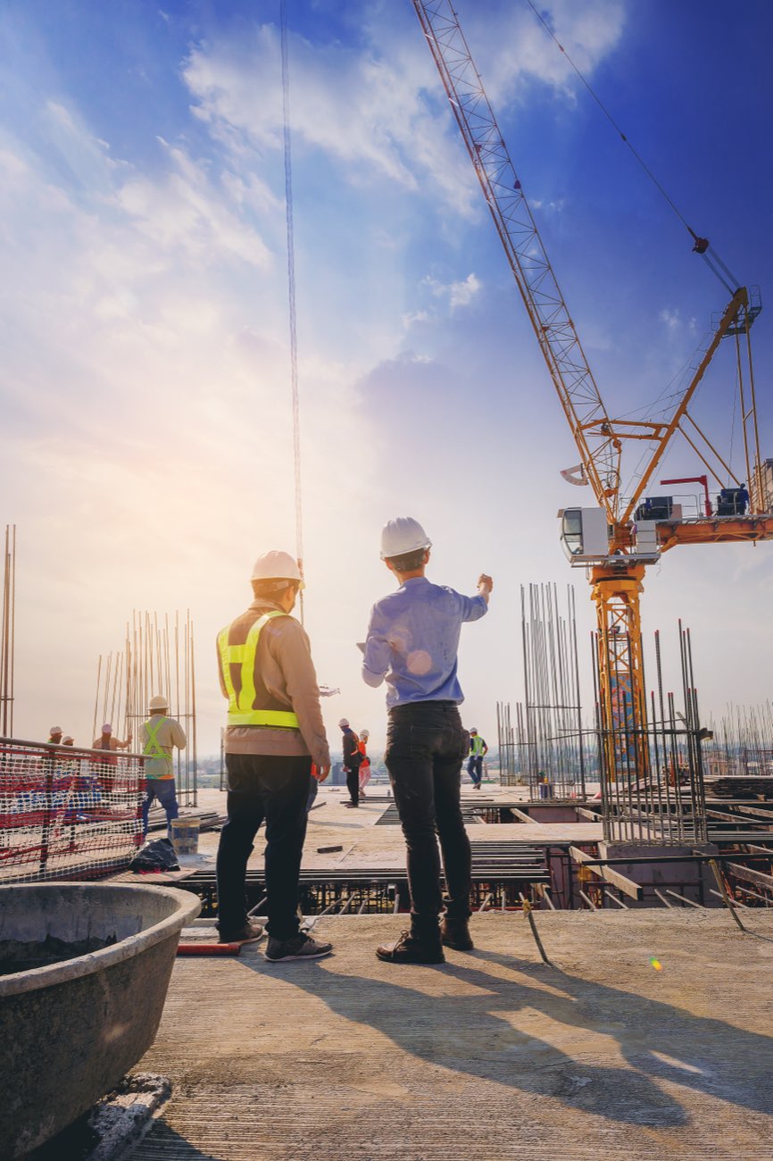 Engineers in hard hats reviewing a construction site with a crane.
